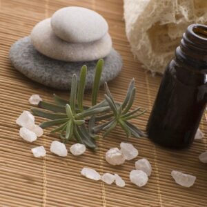 A bottle of essential oil and some rocks on the floor