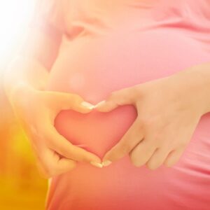 A woman holding her stomach in the shape of heart.