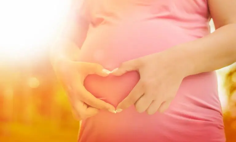 A woman holding her stomach in the shape of heart.