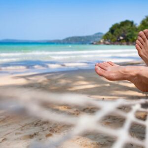 A person laying on the beach with their feet in the air.