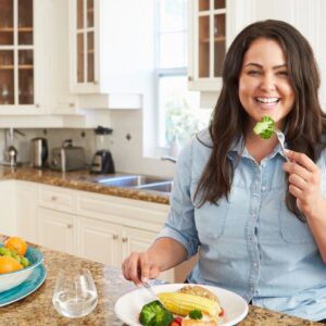 A woman is eating some food in the kitchen