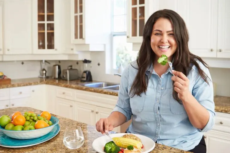 A woman is eating some food in the kitchen