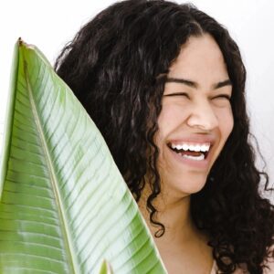 A woman with long hair holding a large leaf.