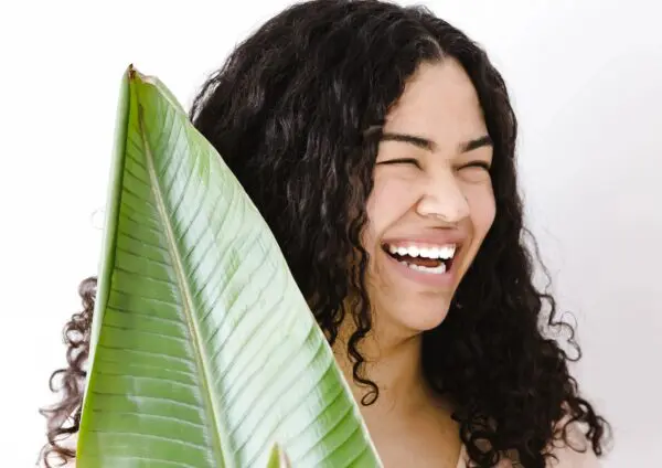 A woman with long hair holding a large leaf.