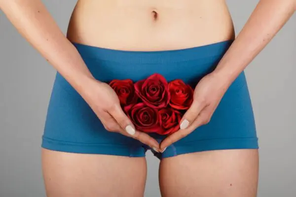 A woman holding roses in her hands and wearing blue panties.