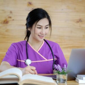 A woman in purple shirt sitting at table with laptop.