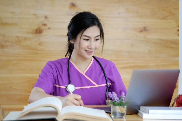 A woman in purple shirt sitting at table with laptop.