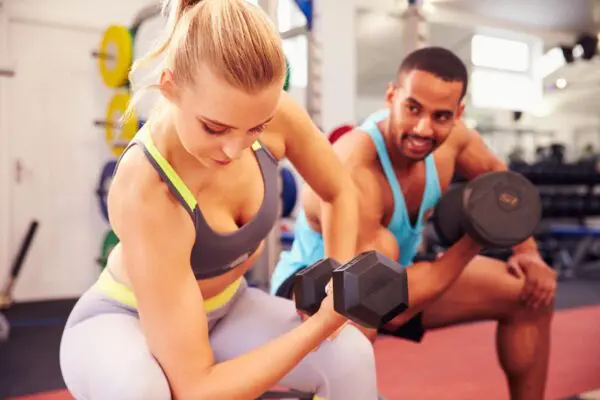 A woman and man are working out with dumbbells.