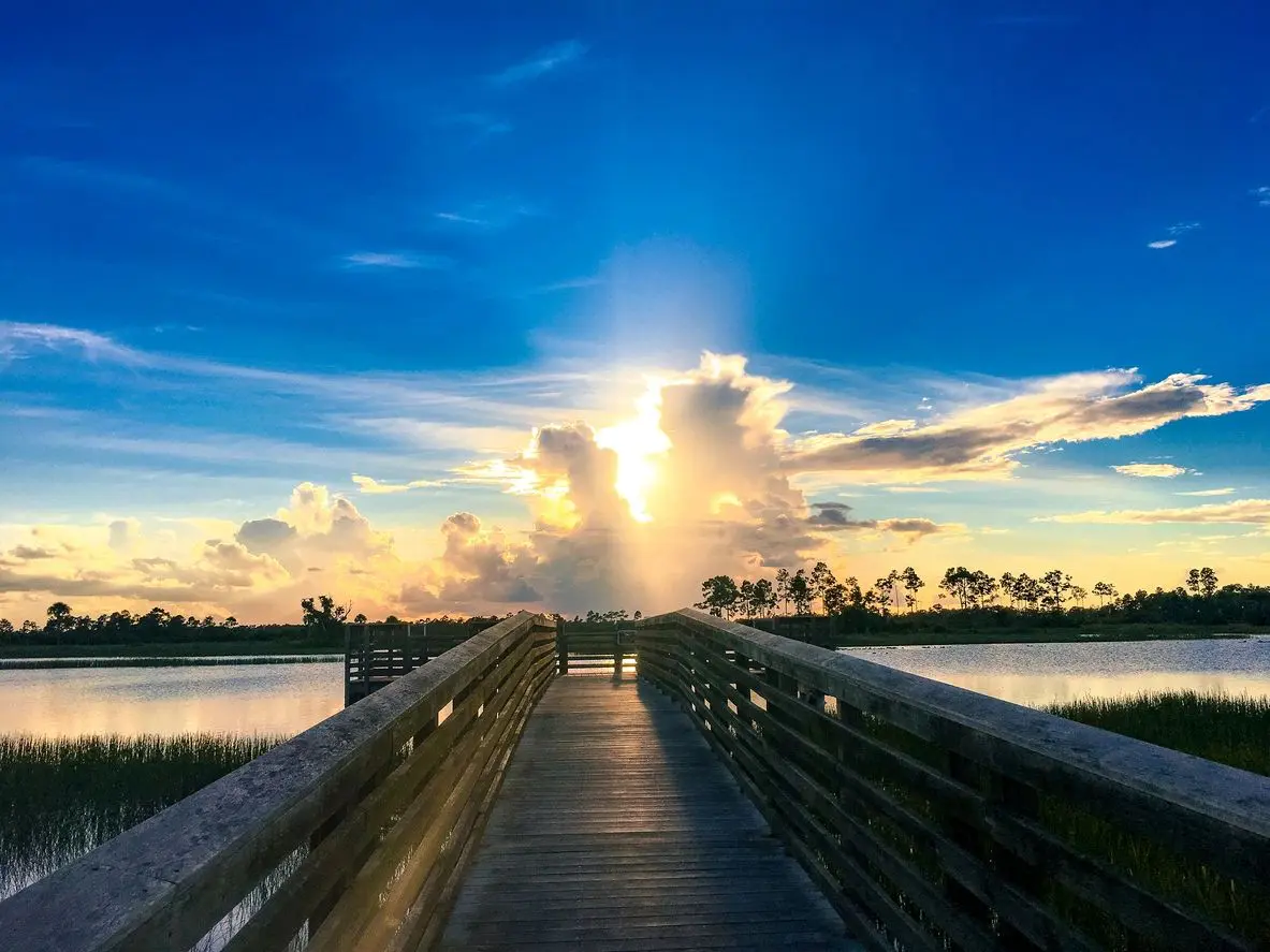 A person walking on the pier at sunset.