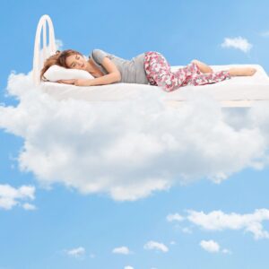 A woman laying on top of a cloud in the sky.