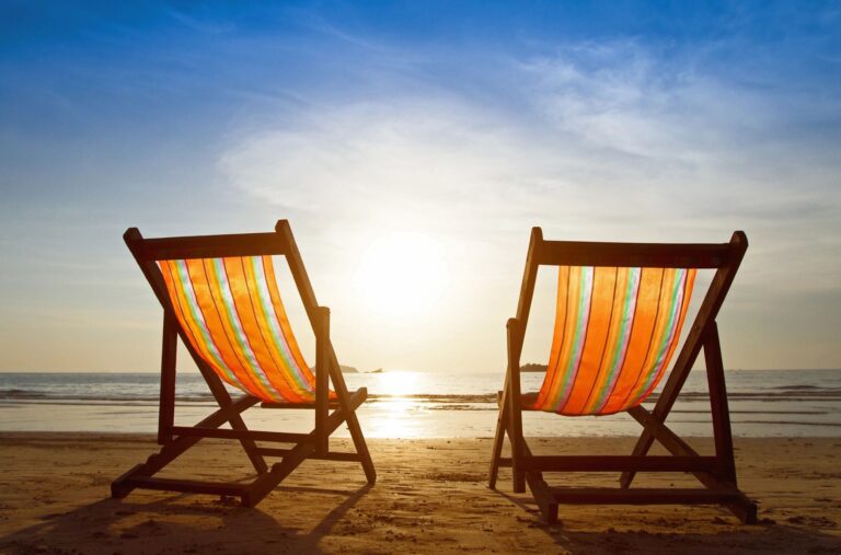 Two chairs on the beach facing each other at sunset.