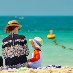 A woman and child sitting on the beach