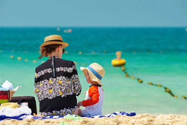 A woman and child sitting on the beach