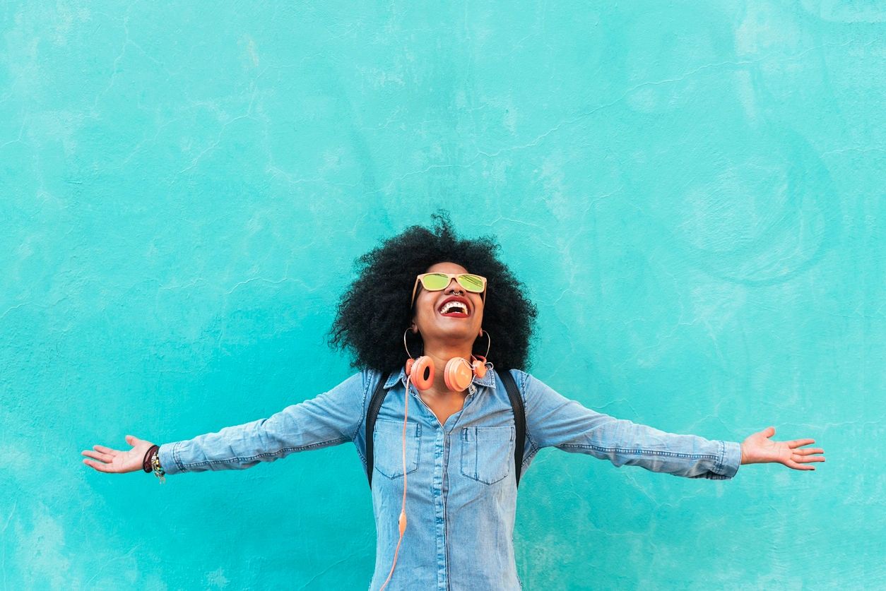 A woman with her arms outstretched and wearing glasses.