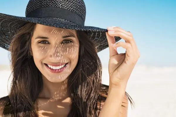 A woman with sun cream on her face and hat.