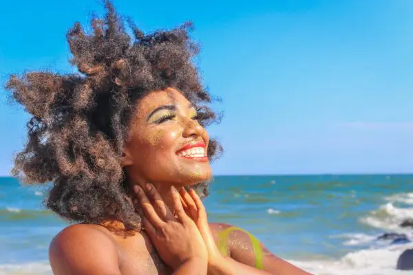 A woman with her hands on her face and smiling.