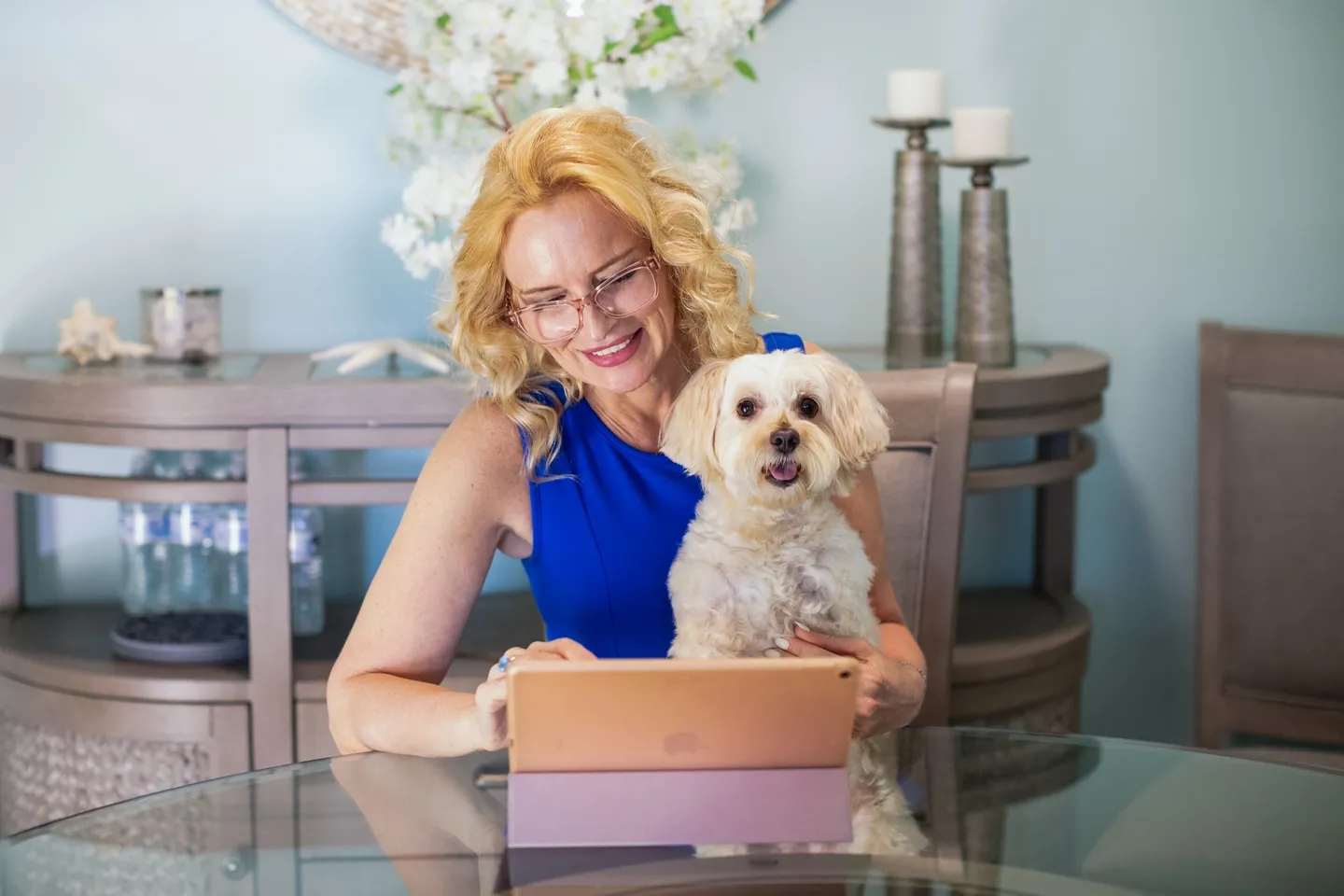 A woman sitting at the table with her dog.