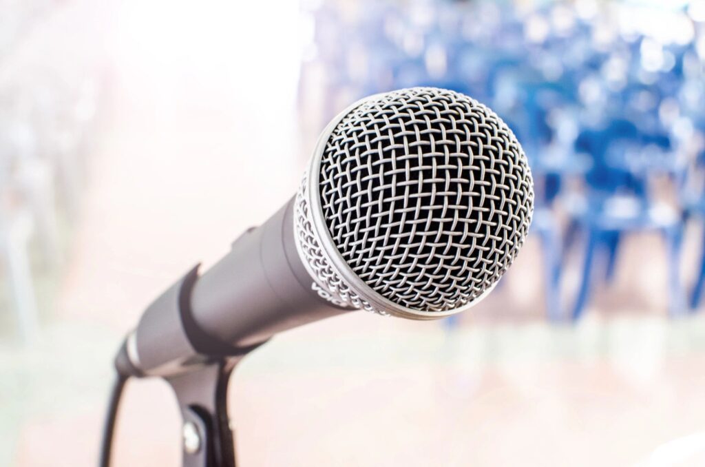 A microphone is on the stand in front of some flowers.