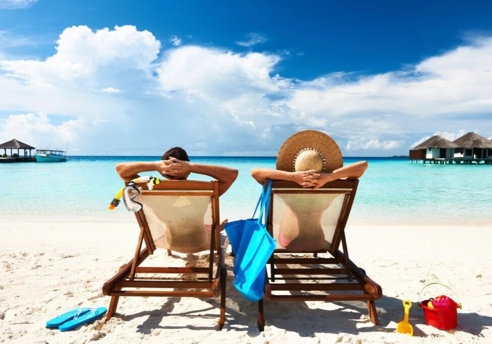 Two people sitting in lawn chairs on the beach