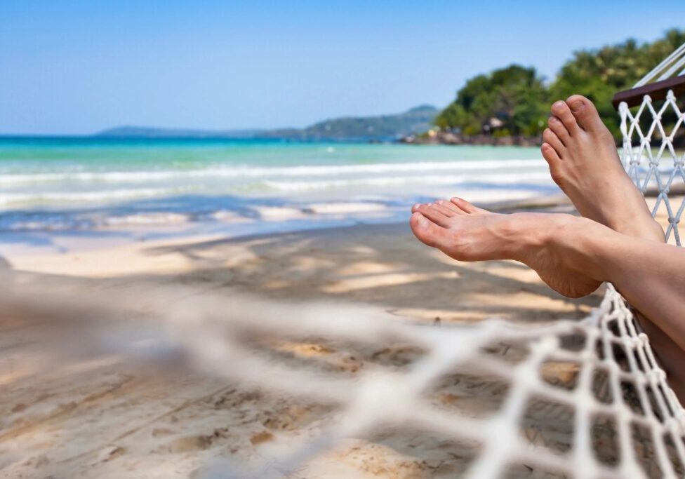 A person laying on the beach with their feet in the air.