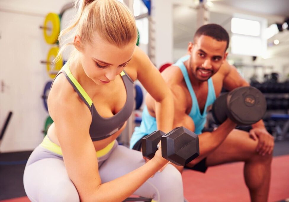 A woman and man are working out with dumbbells.