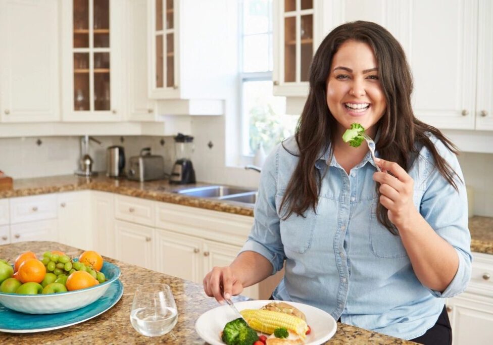 A woman is eating some food in the kitchen