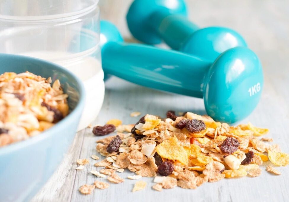 A bowl of cereal and two blue dumbbells.