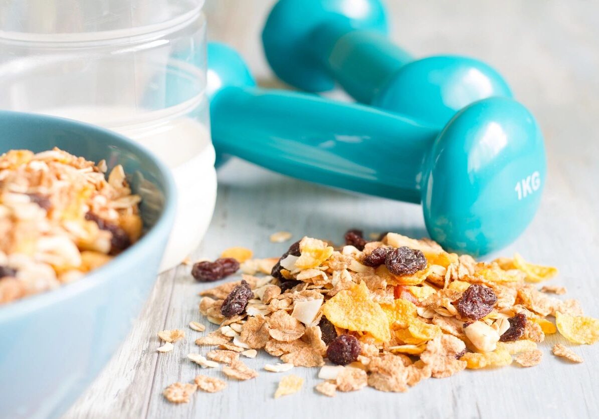 A bowl of cereal and two blue dumbbells.