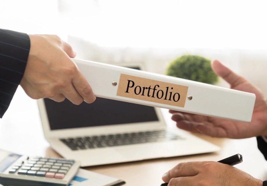 A person is holding onto a folder with the word portfolio on it.