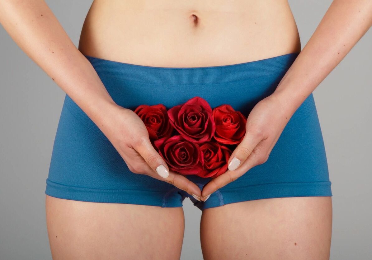 A woman holding roses in her hands and wearing blue panties.