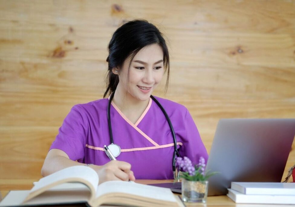 A woman in purple shirt sitting at table with laptop.